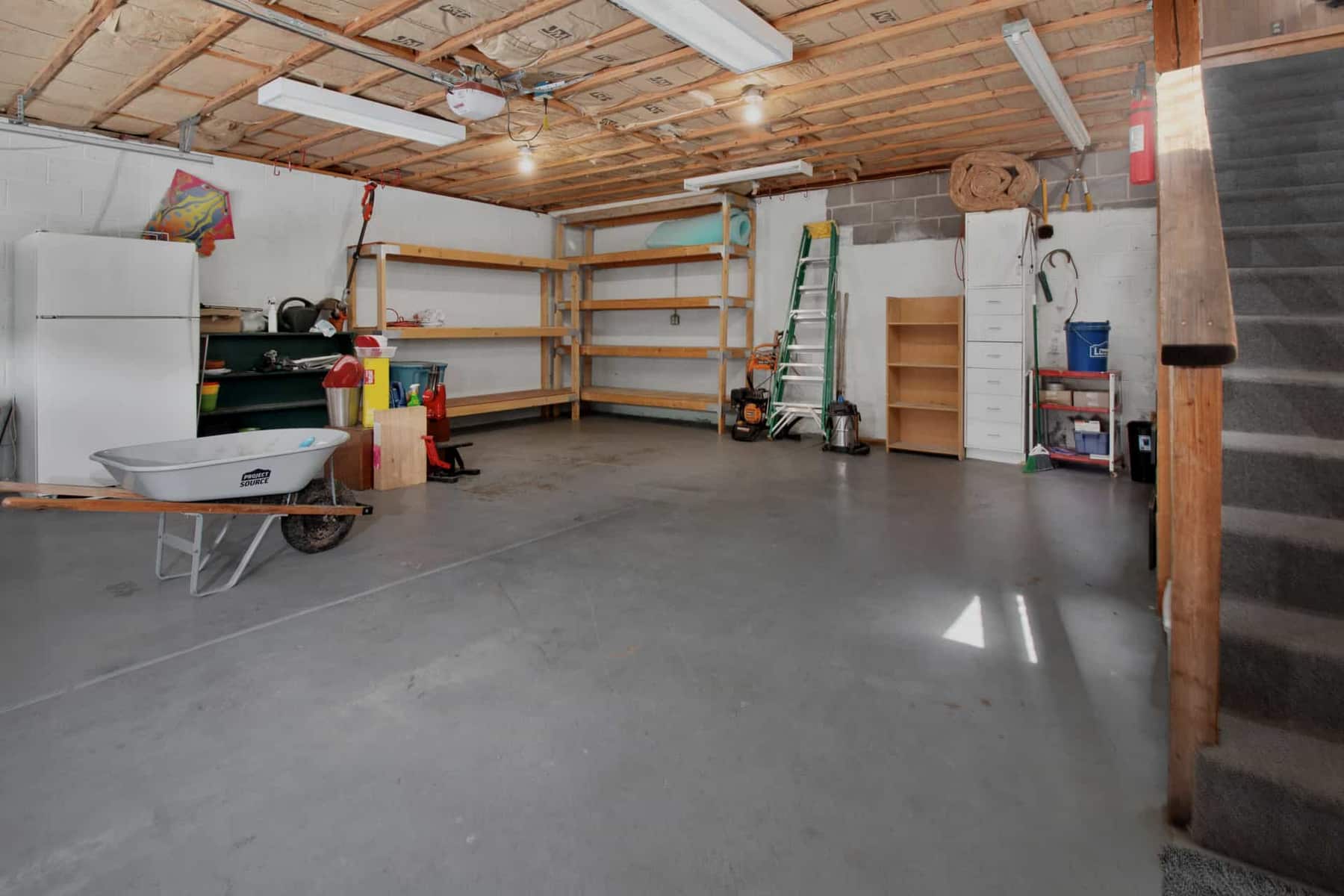 An organized garage with overhead racks, wall storage and shelving in use